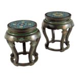 A near pair of Chinese lacquer stands, each with a cloisonné circular top decorated with flowers,