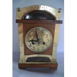An Arts & Crafts mantle clock in oak with applied brass detail, with embossed brass dial over a