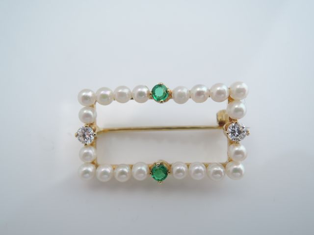 An emerald, diamond and pearl brooch, the open worked rectangular frame set with twenty pearls,