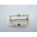 An emerald, diamond and pearl brooch, the open worked rectangular frame set with twenty pearls,