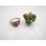 A jade ring, claw-set with three oval cabochon jade stones, highlighted with stylised leaves, in