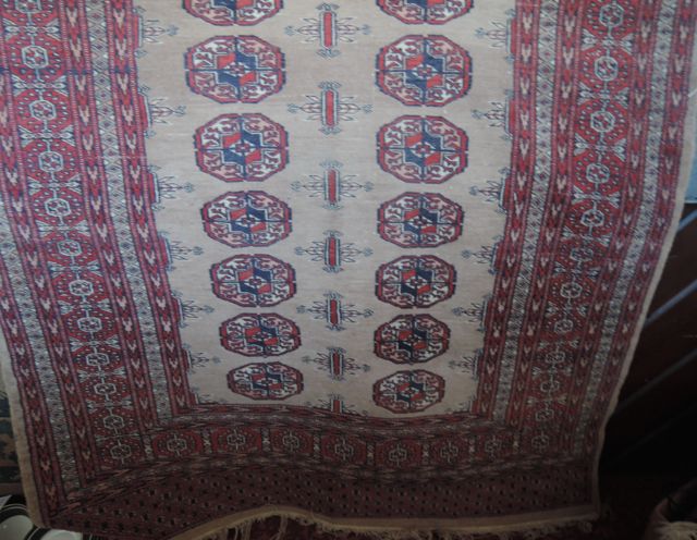 An Afghan style wool rug on a beige field, with multi-medallion detail, set within alternating