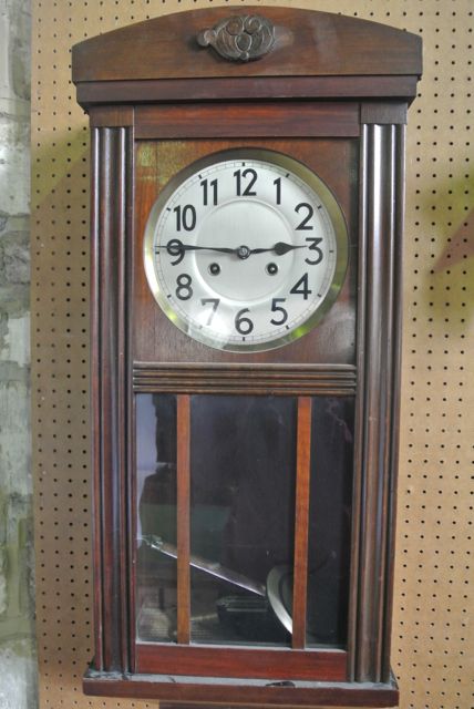 A 1920s wall clock with moulded framework, the anodised dial enclosing an eight day striking