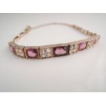 An Edwardian style bracelet, set with five graduated mixed-cut untested possibly rhodolite
