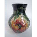 A Moorcroft dark blue ground vase with moulded and painted stylised floral design in the