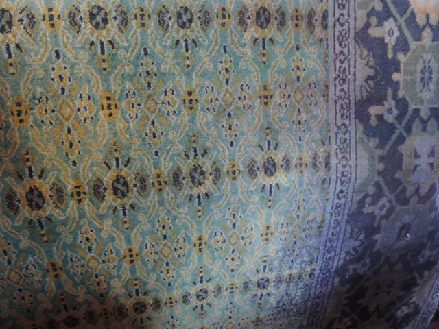 A Persian style wool carpet with pale green field and geometric detail, set within bold running