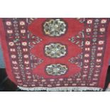 A small Persian style red wool rug with deep red ground, multi-medallion centre, set within