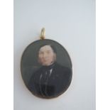 A mid Victorian portrait miniature pendant, of a gentleman in a black jacket, in a plain gold-plated
