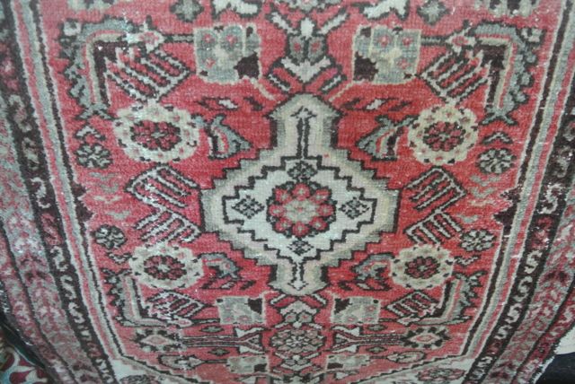 A small wool carpet in the Persian style with red ground field, geometric detail, set within running