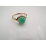 A gem-set ring, centred with a green cabochon stone, in 18ct gold, size P