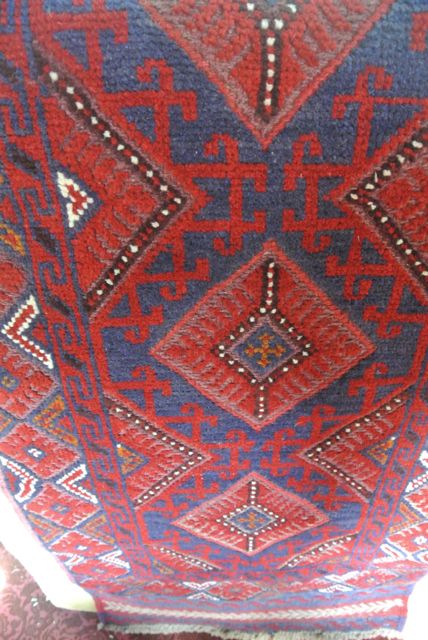 A wool rug in the eastern style, the red ground overlaid with geometric detail, principally in a