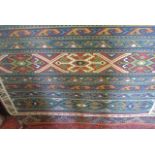 A Persian style rug with banded panels in reds and blues, further geometric detail, set within white
