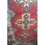 A Persian wool rug with red field, geometric cross detail, set within running borders, 190 x 75 cm