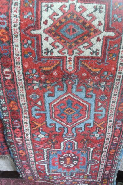 A Persian style wool runner with multi-medallion centre upon a red field within further geometric