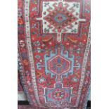 A Persian style wool runner with multi-medallion centre upon a red field within further geometric