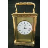 A French brass carriage clock with chased case, the circular enamel dial within an engine turned