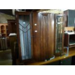 An Art Deco style veneered side cabinet partially enclosed by a pair of slender glazed panelled