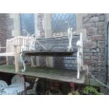 A Victorian style garden bench with weathered timber slatted seat and combined back raised on