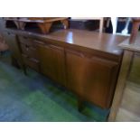 A long and low mid to late 20th century teak sideboard enclosed by an arrangement of cupboards and