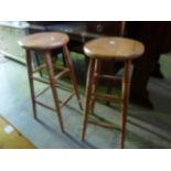 A pair of contemporary beech high kitchen stools with circular seats and turned tapered supports