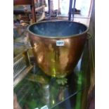 A copper and brass cauldron shaped coal bucket with riveted detail and lions paw feet