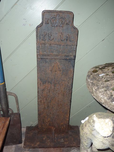 A cast iron marker with relief lettering ER flanking a crown and initialled for feet & inches