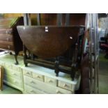 An antique oak oval drop leaf gateleg dining table with single end frieze drawer raised on turned