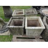 A set of four weathered cast composition stone planters of square cut form with raised relief