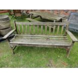 A weathered teak three seat garden bench with slatted seat and back