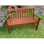 A contemporary stained hardwood two seat garden bench with slatted seat and back