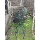 An ironwork garden table of circular form raised on four swept and scrolled supports beneath a glass