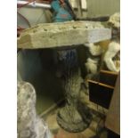 A weathered cast composition stone bird bath of octagonal form with foliate relief detail raised