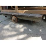 A vintage platform trolley with weathered timber bed raised on cast iron wheels