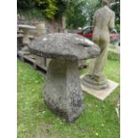 A weathered natural stone staddle stone and domed cap (one piece, top segmented to base)