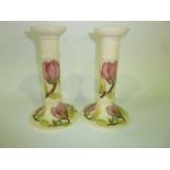 A pair of Moorcroft cream ground candlesticks in the Magnolia pattern with impressed and painted