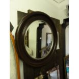 A large contemporary wall mirror of circular form with moulded frame enclosing a bevelled edge