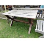 A weathered teak garden table, the rectangular slatted top raised on x framed supports united by a