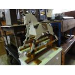 A vintage child's wooden rocking horse with painted dappled finish, simple tan leather saddle and