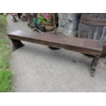 A pair of vintage stained pine benches with plank seats, shaped end supports with wedge feet