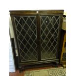 An early 20th century oak freestanding bookcase enclosed by a pair of rectangular leaded light