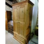 A stripped pine wardrobe with moulded cornice over a pair of three quarter length rectangular twin