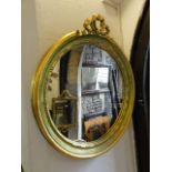 A circular wall mirror with moulded frame, tied ribbon surmount and gilt finish together with one