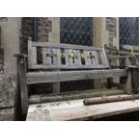 A weathered softwood garden bench, with slatted seat and pierced fleur-de-lys splats