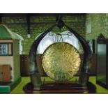 A Victorian brass table gong with textured finish flanked and supported by  a pair of polished