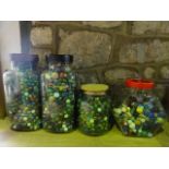 Four large glass jars containing a large collection of vintage glass marbles of varying size and