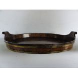 A good quality antique mahogany tray of oval form with raised sides and scrolling handles, with