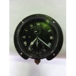 An unusual circular cased car clock with black ground and white enamelled roman numeral dial set
