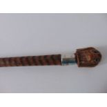 A timber walking cane with incised detail terminating in a carved timber finial in the form of a