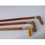 Three Malacca walking canes, two with worked antler handles, each with white metal collars