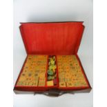 A vintage composition Mahjong set contained within a stitched leather case with applied paper